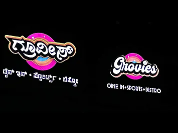 Backlit sign board at night with glowing white Kannada and English lettering for Grovies, a dine-in sports bistro